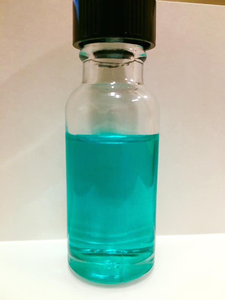 Picture of clear glass bottle filled with aquamarine frankincense